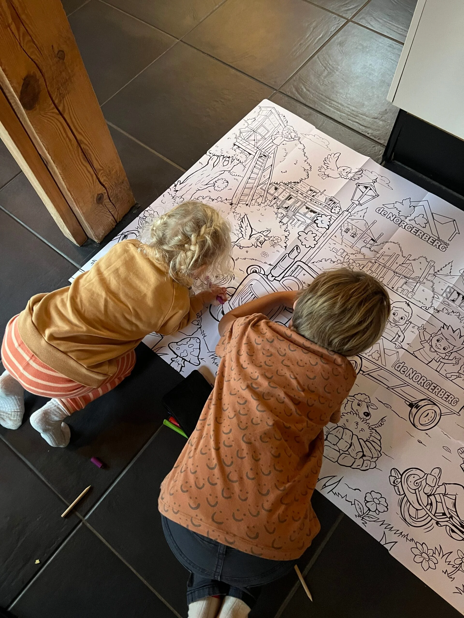 Kinderen kleuren op een grote kleurplaat van de Norgerberg in vakantiehuisje De Hooikiep