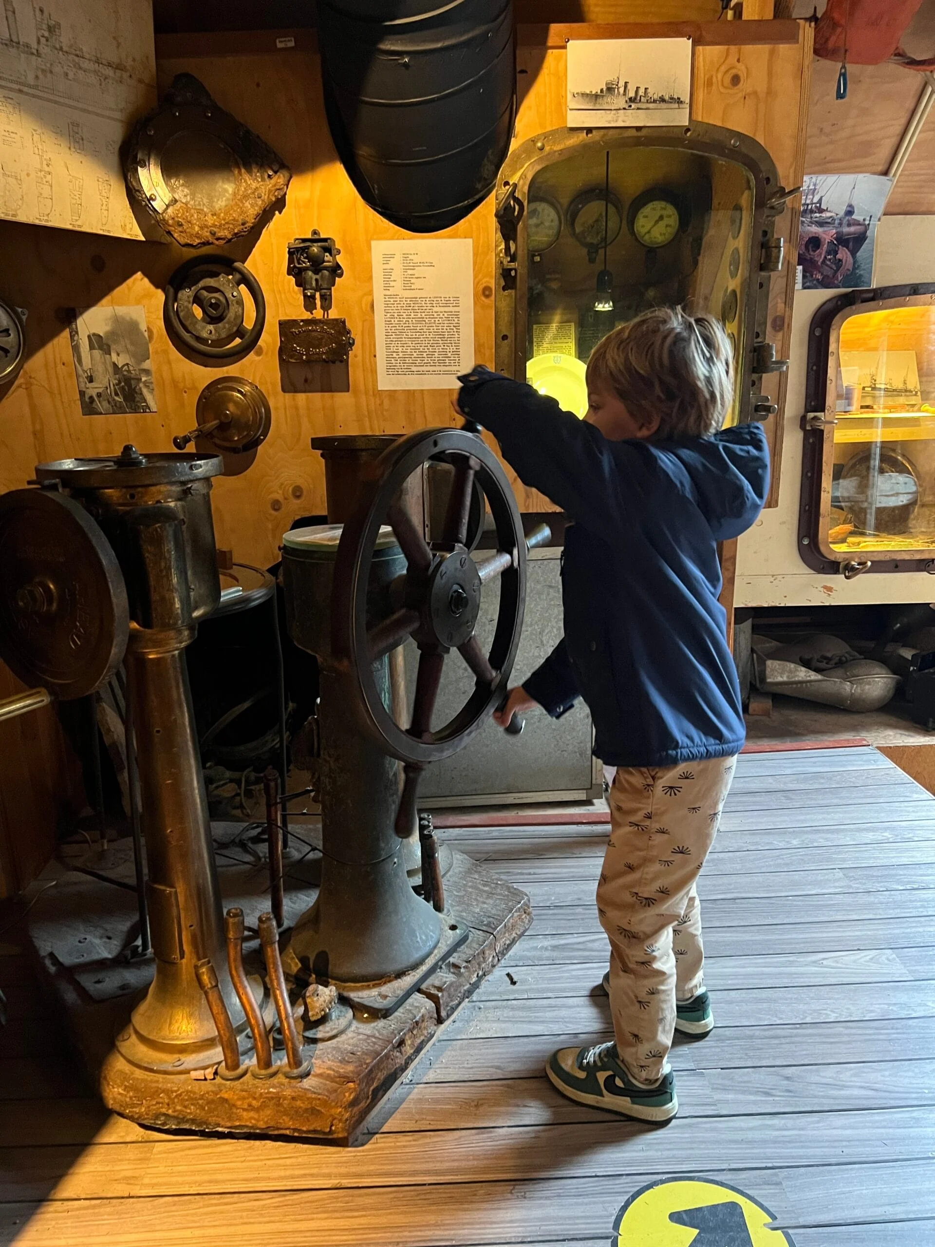 Kind staat aan het roer van een oud schip