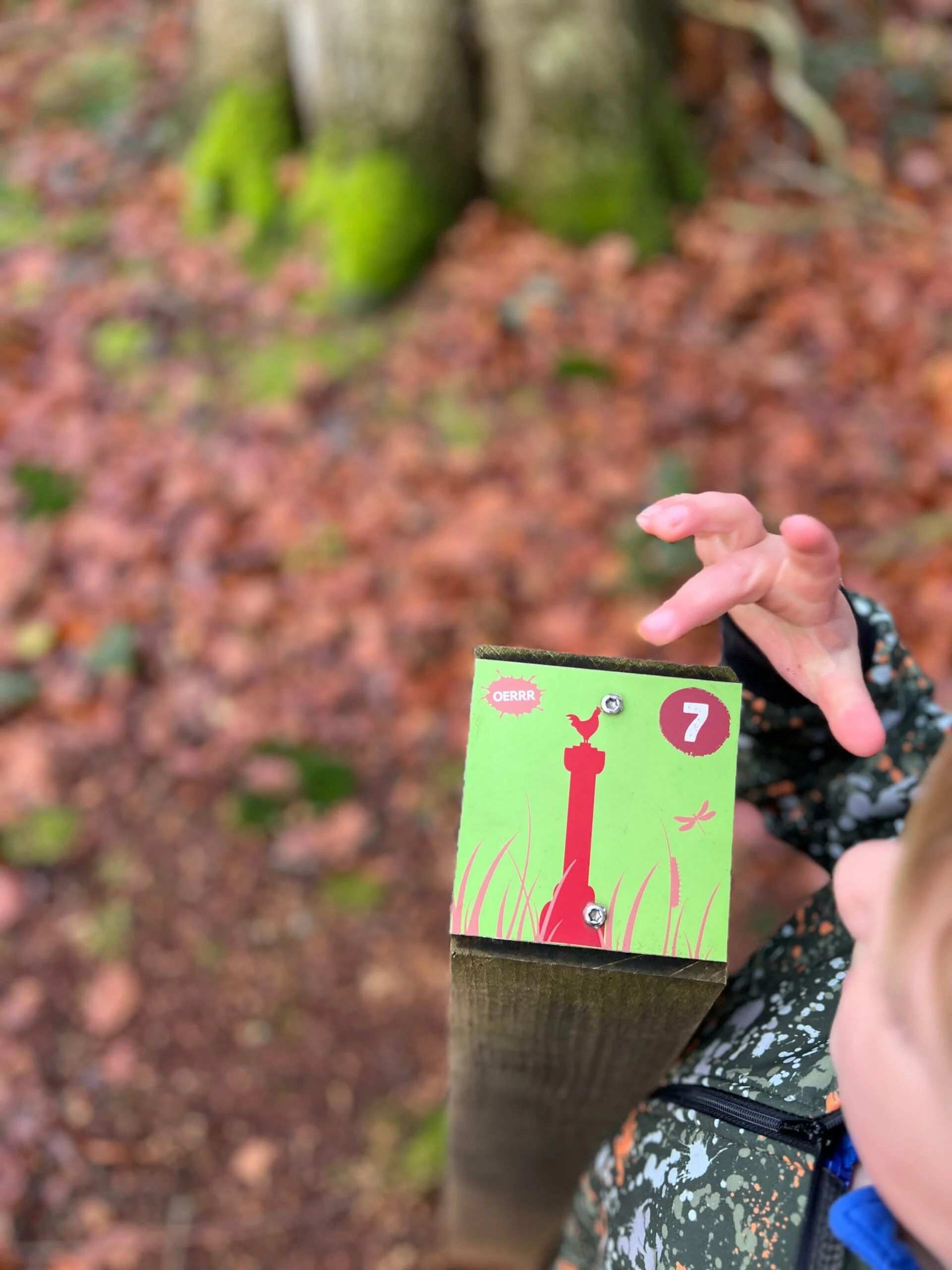Kind staat bij een bordje van de wandelroute in de speelnatuur van OERRR bij Bakkeveen