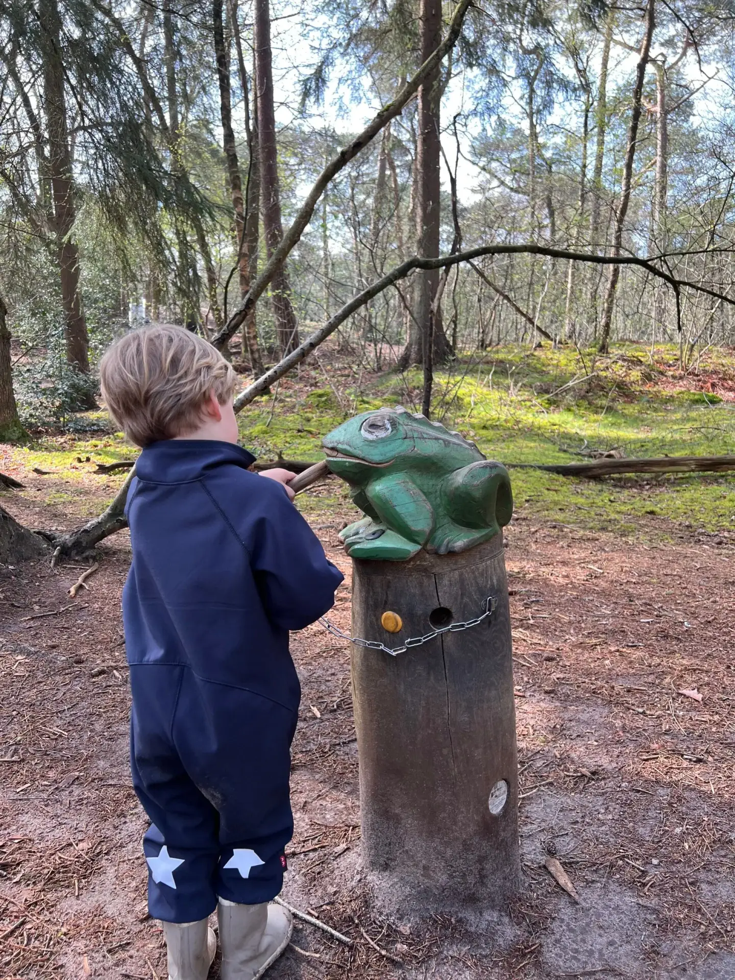 Kind maakt geluid bij een houten kikker op het Struin- en Duinpad in Norg, Drenthe