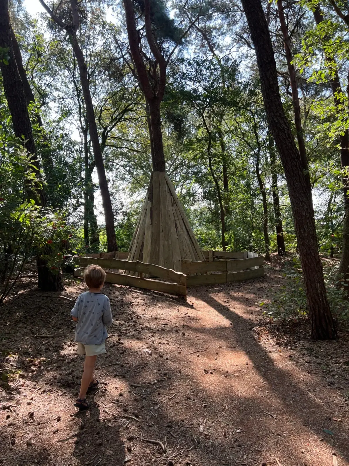 Kind loopt naar houten tipi op het belevingspad de Ipadweg in Veeningen, Drenthe