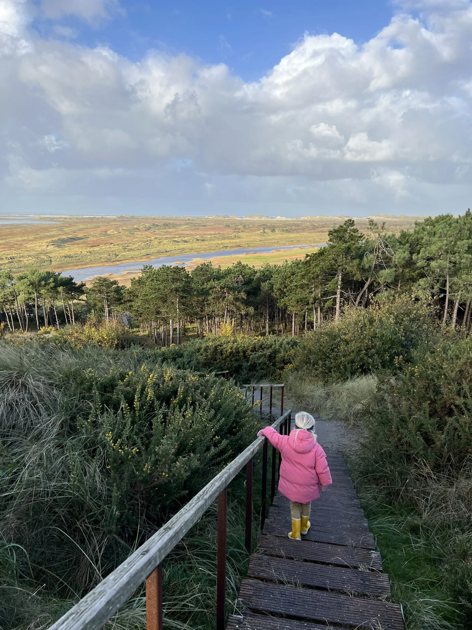 Kind loopt de trap op van de Seinpaalduin op Terschelling met uitzicht op de Boschplaat