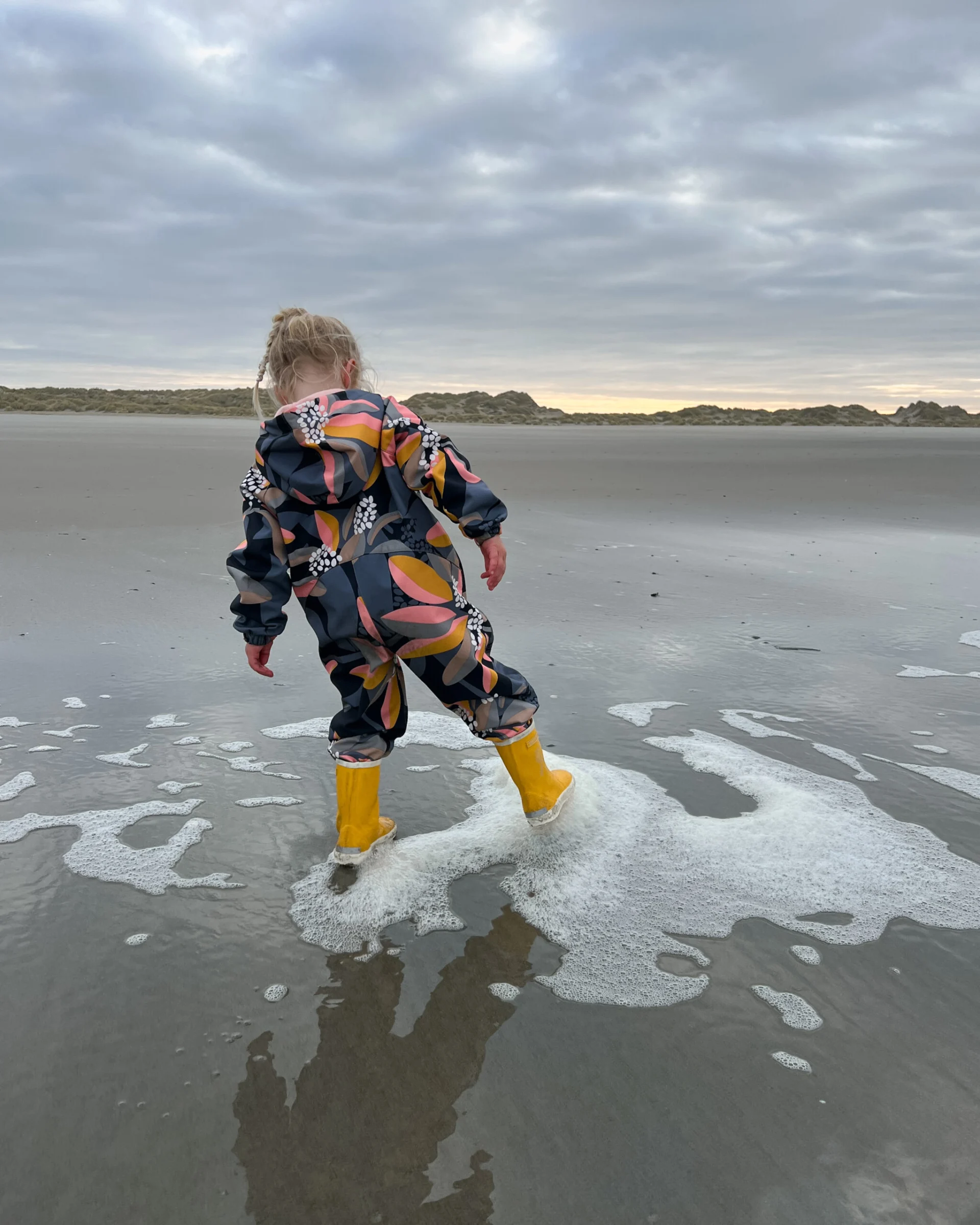 Kind draagt een buitenpak van Ielm op het strand van Terschelling