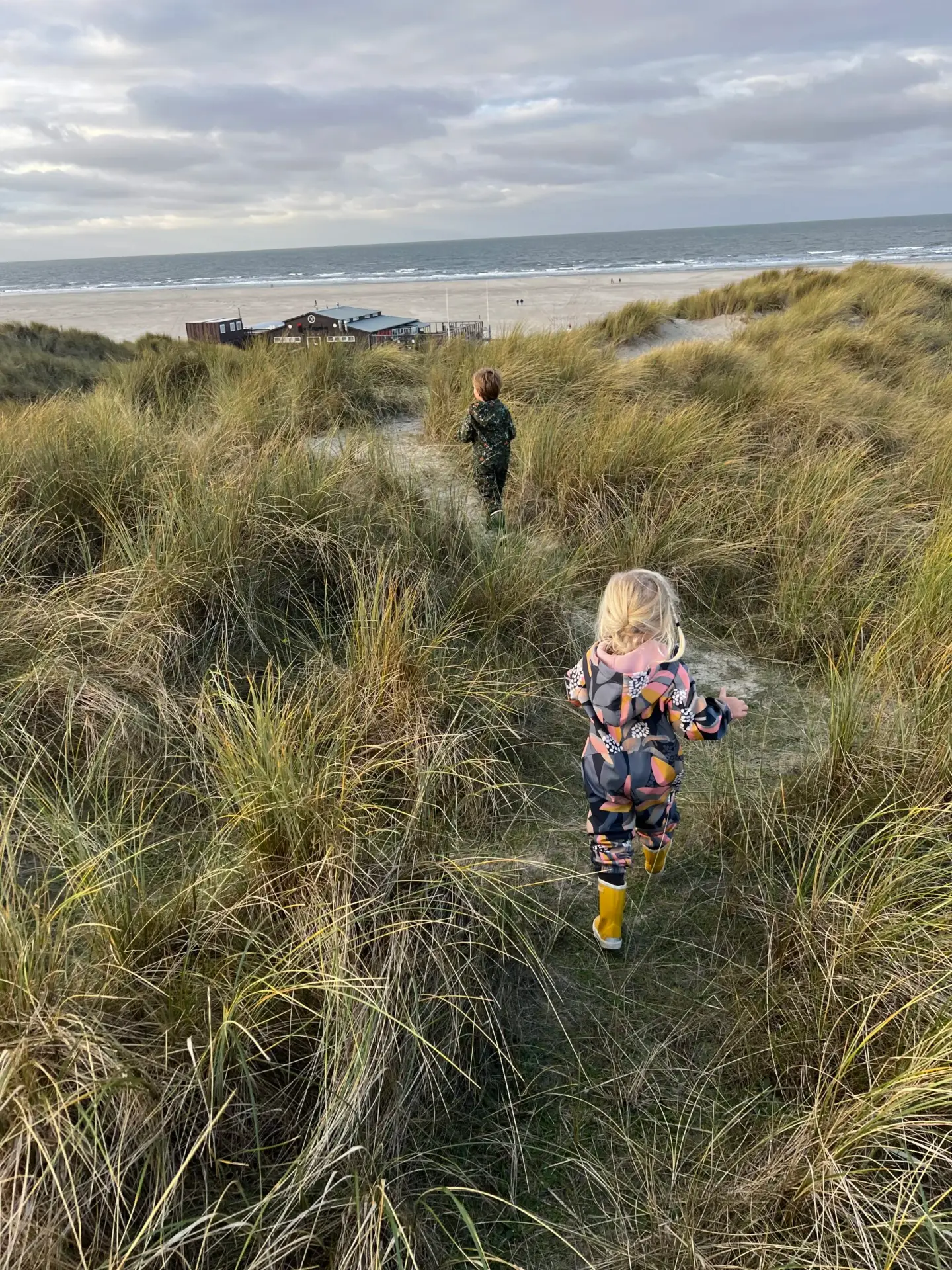 Twee kinderen lopen door de duinen bij het strand van Terschelling bij Midsland aan Zee