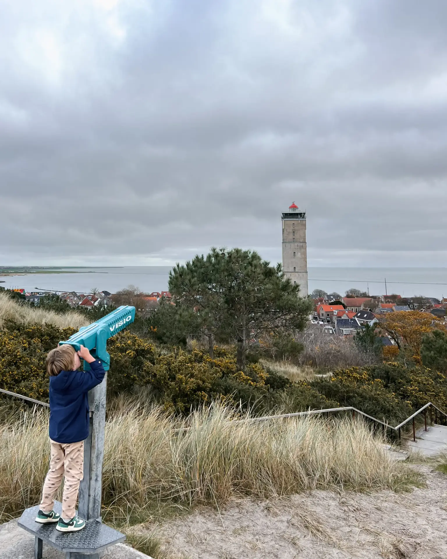 Uitkijkpunt Terschelling – kind kijkt naar de Brandaris Kind kijkt door een verrekijker naar de Brandaris vanaf een duinuitkijkpunt op Terschelling