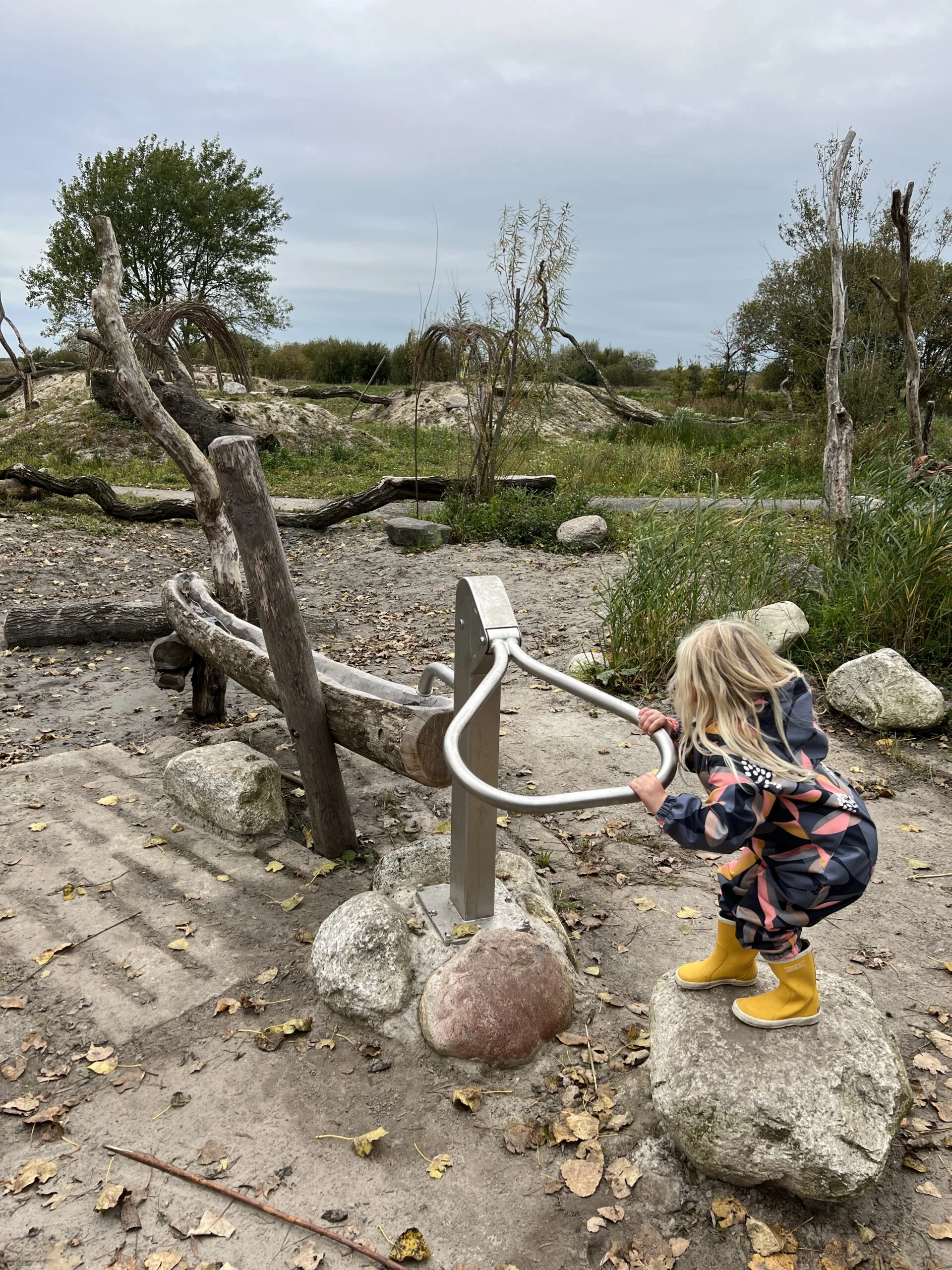Kind speelt bij de waterpomp in de speelnatuur van OERRR bij De Onlanden in Groningen