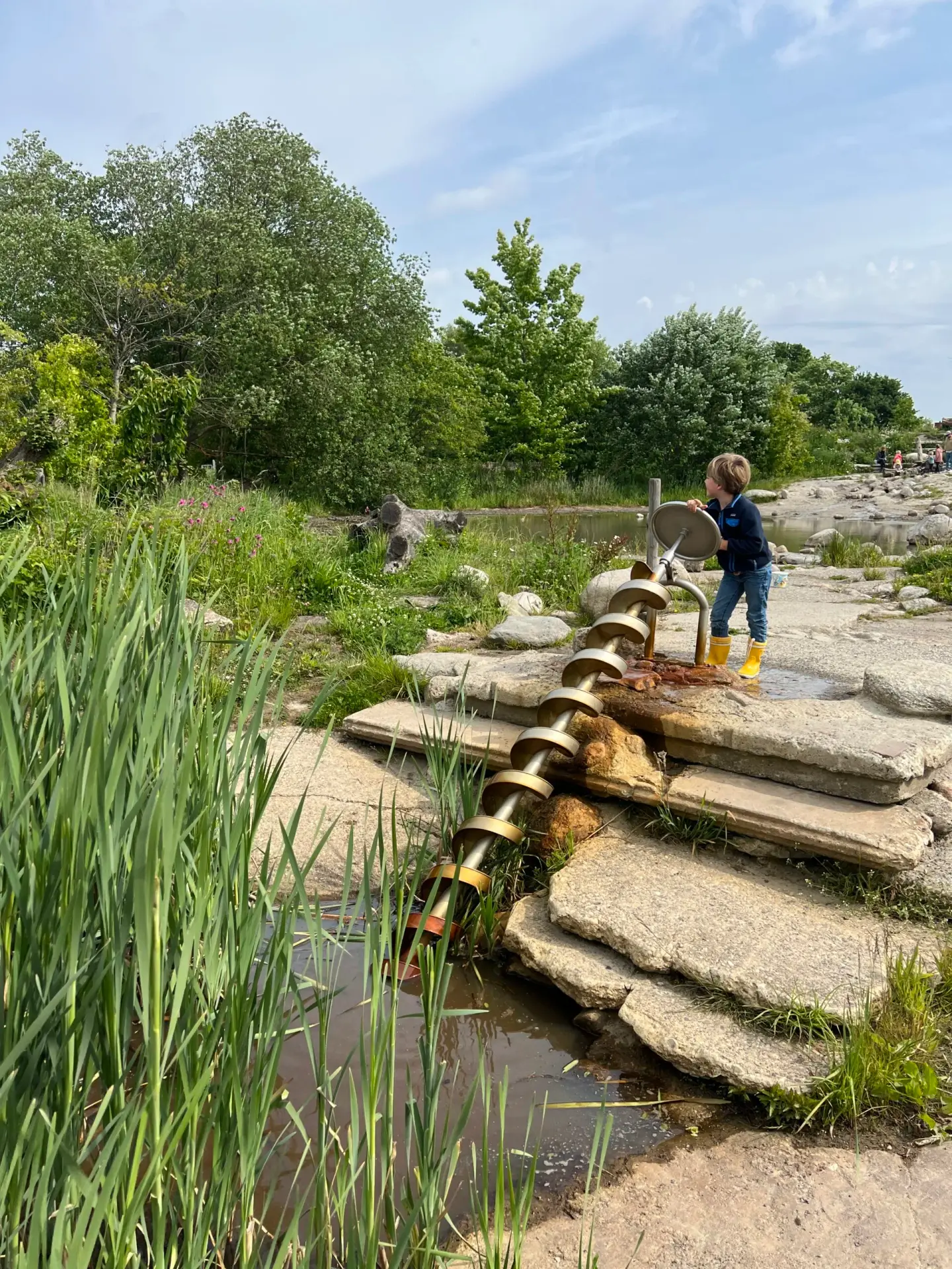Kind speelt bij de waterpomp in de natuurspeeltuin in het noorden van Nederland
