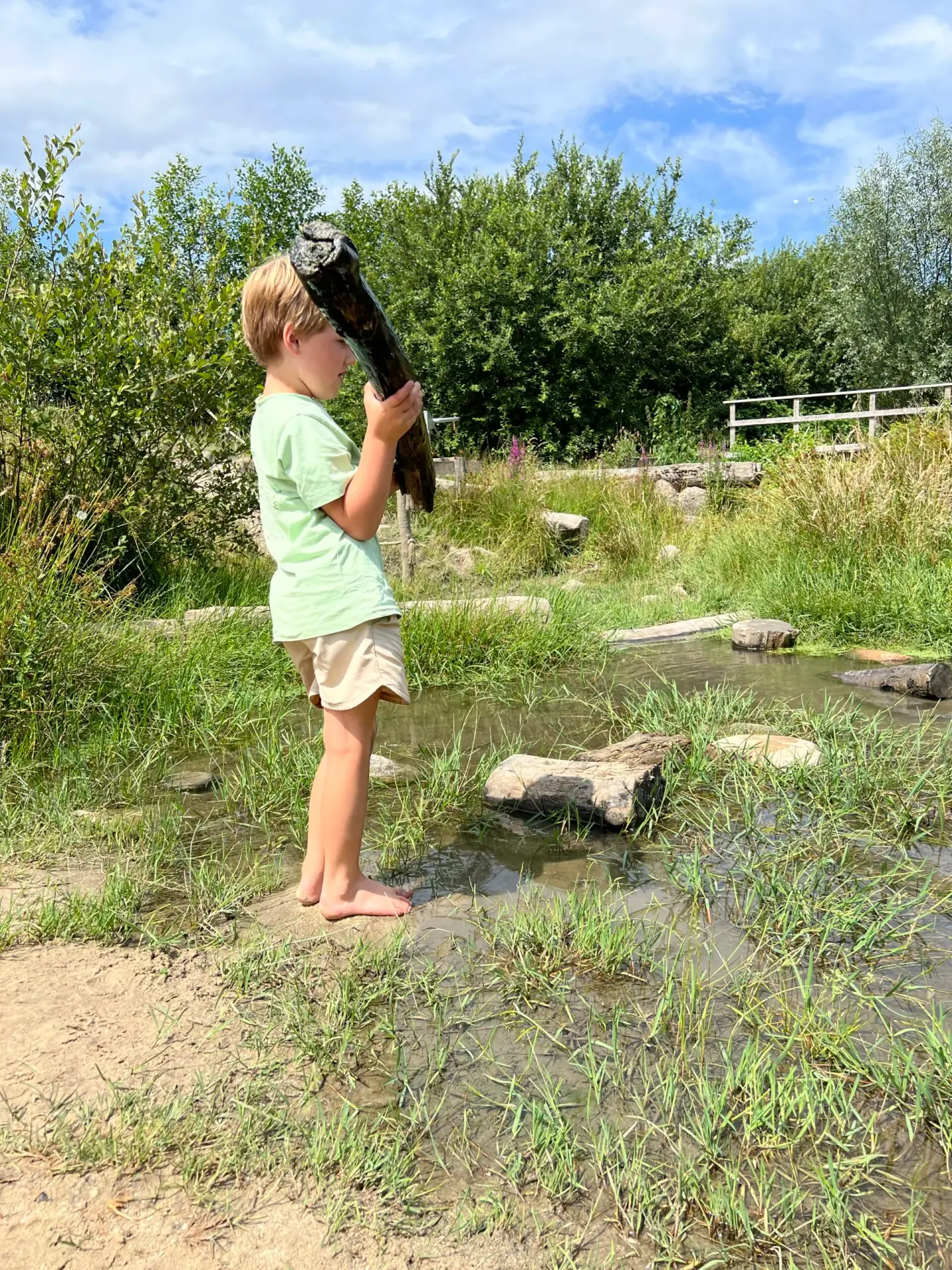 Kind speelt met boomstammetjes in de natuurspeelplaats in Drenthe