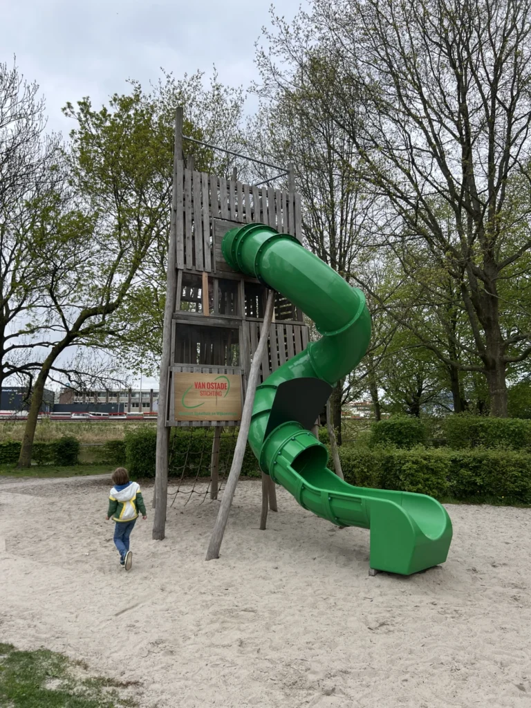 Grote groene glijbaan in een speeltuin in de Schildersbuurt in Groningen