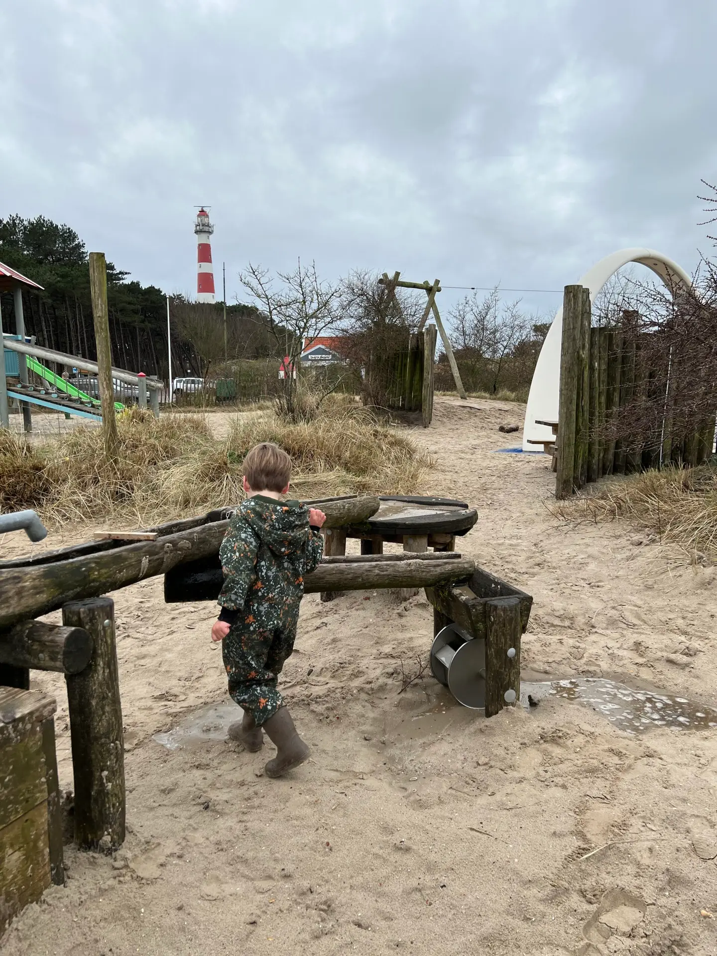 Kind speelt in speeltuin van Landal op Ameland met de Vuurtoren van Ameland op de achtergrond. Mooie plek om te overnachten op Ameland met kinderen. 