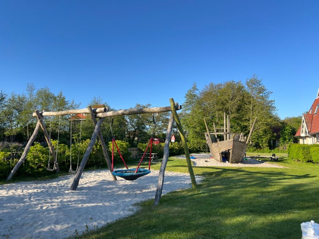 Speelplek met schommels en houten speelschip op Vakantiepark Tjermelân in Oosterend, fijne uitvalsbasis voor een weekend op Terschelling met kinderen
