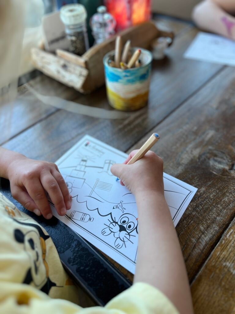 Kind maakt een tekening bij strandpaviljoen De Branding bij Midsland aan Zee op Terschelling