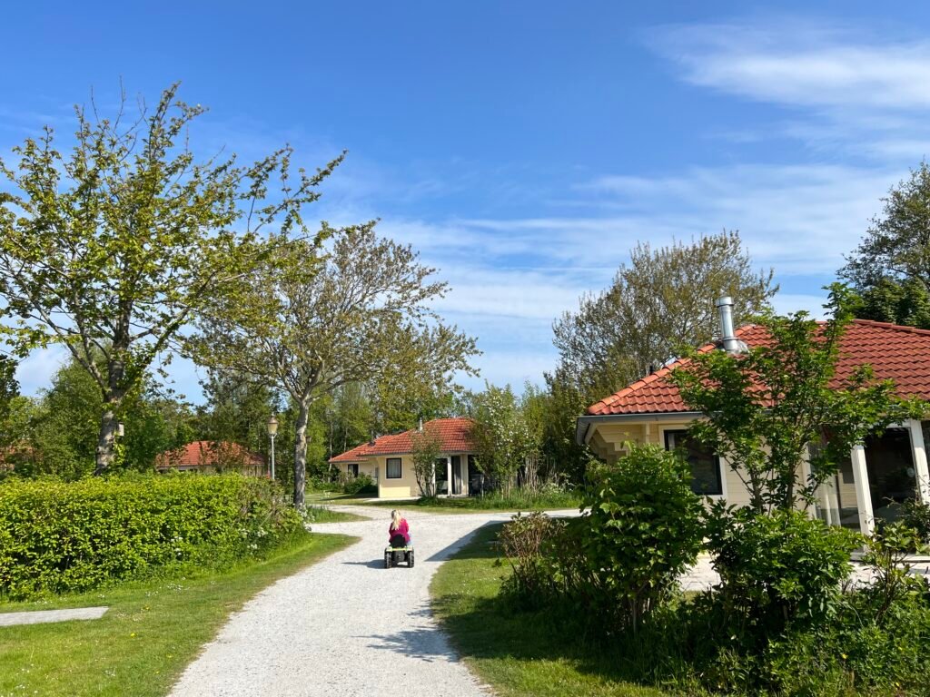 Kind rijdt op een speelgoedtractor tussen de bungalows van Vakantiepark Tjermelân op Terschelling