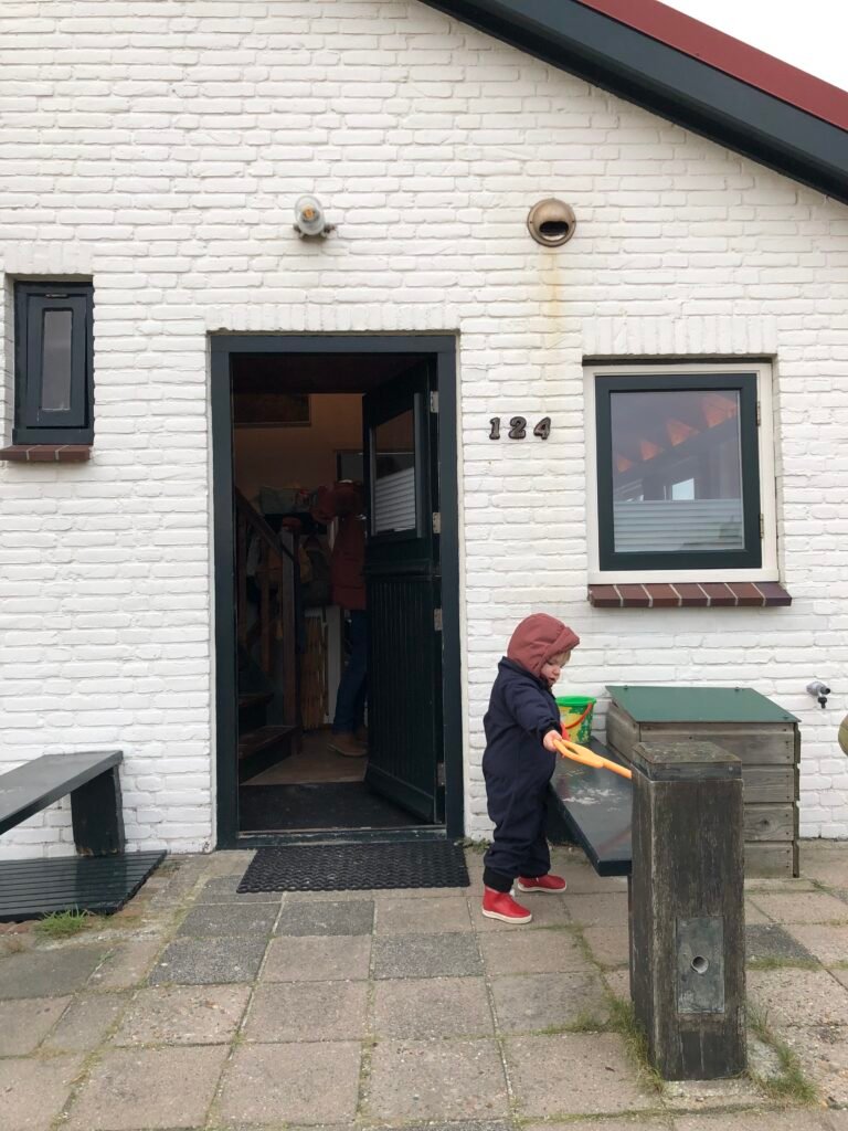 Kind komt naar buiten bij voordeur van vakantiehuisje in de duinen