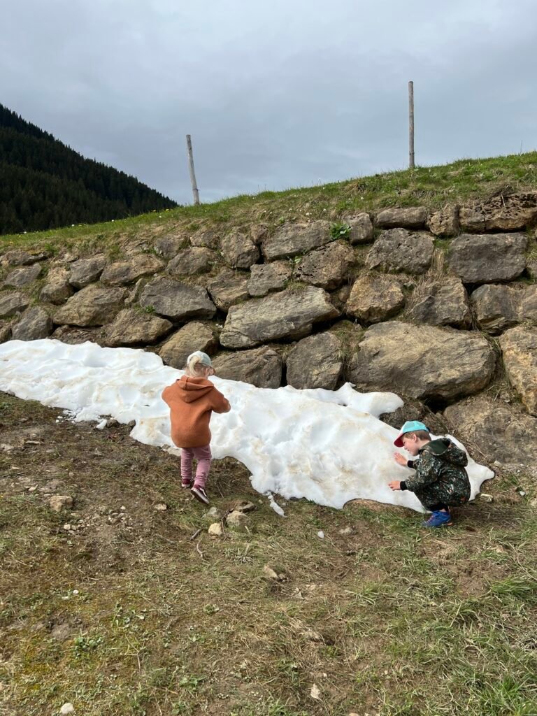 Kinderen spelen in de sneeuw in de bergen van Allgäu in Beieren in mei