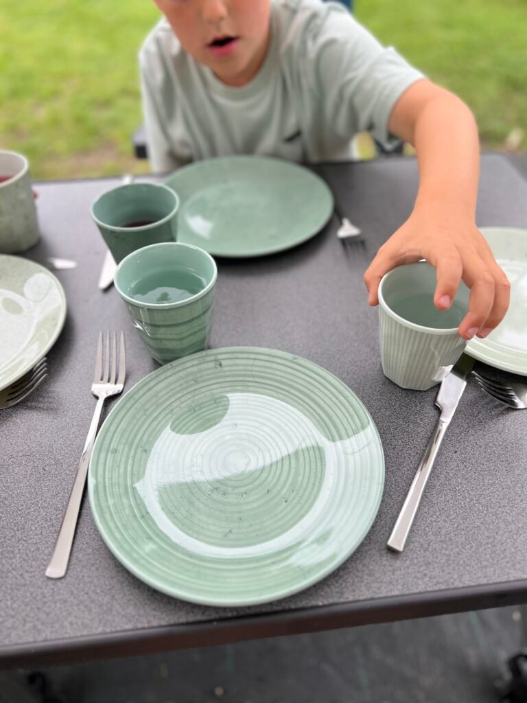 Campingservies met bestek op tafel, handige kampeerspullen
