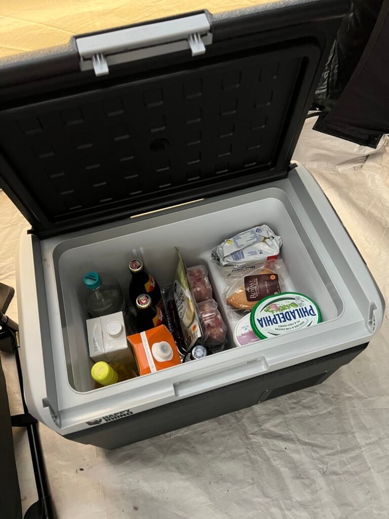 Elektrische koelbox vol boodschappen in de tent op de camping, Handige kampeerspullen