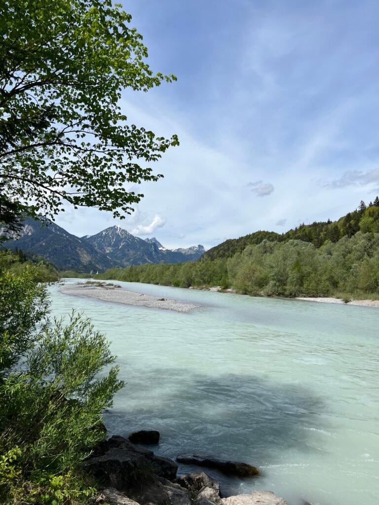 Helderblauw smeltwater van de rivier de Lech met de Alpen op de achtergrond op de grens van Duitsland en Oostenrijk