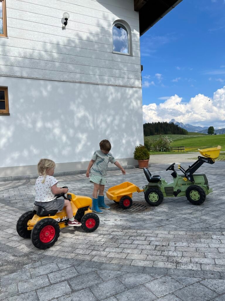 Kinderen spelen op speelgoedtractors bij een verblijf in Hopferau in Allgäu, Beieren in Zuid-Duitsland