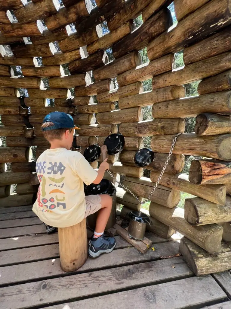 Kind speelt op houten drumstel in de muziek-boomhut van het belevingspad in Tirol