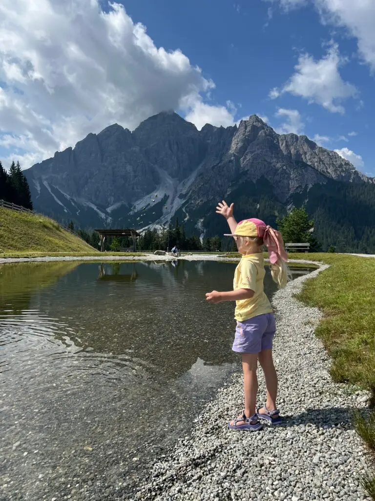 Kind met Teva sandalen bij een bergmeer in Oostenrijk tijdens een vakantie in de bergen met kinderen