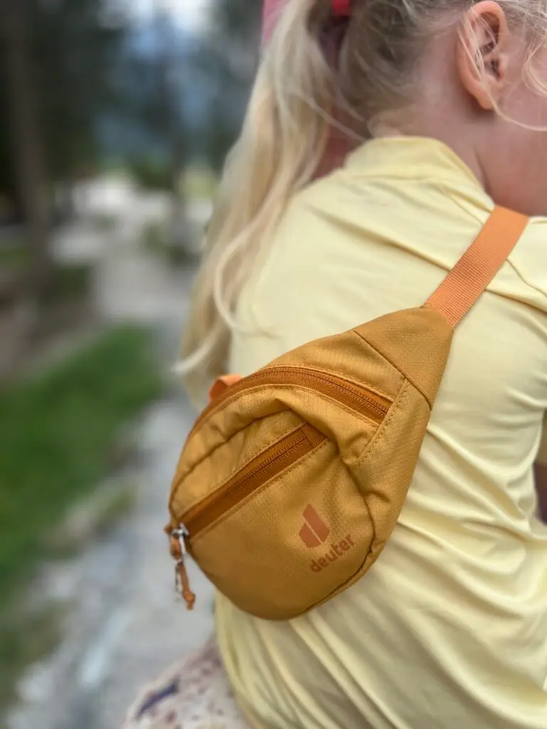 Kind met okergele Deuter junior heuptas tijdens een vakantie in de bergen met kinderen