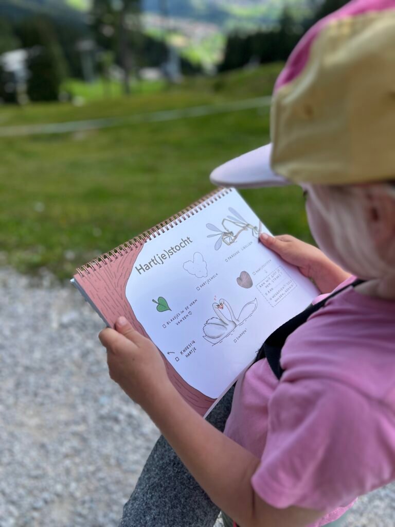 Kind met het zoekboek Expeditie Natuur en een zoekplaat voor een speurtocht