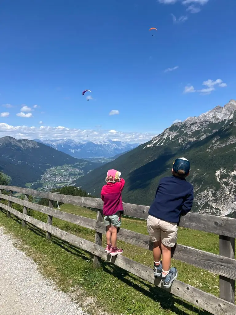 Kinderen met fleece vest en pet kijken uit over dal in Stubai