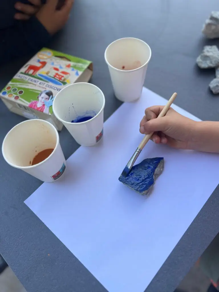 Kind verft een steen met natuurlijke verf tijdens een kinderfeestje
