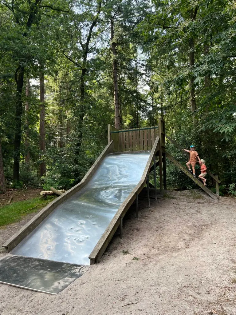 Kinderen lopen de trap op van de glijbaan in de speeltuin Blauwe Bos Friesland