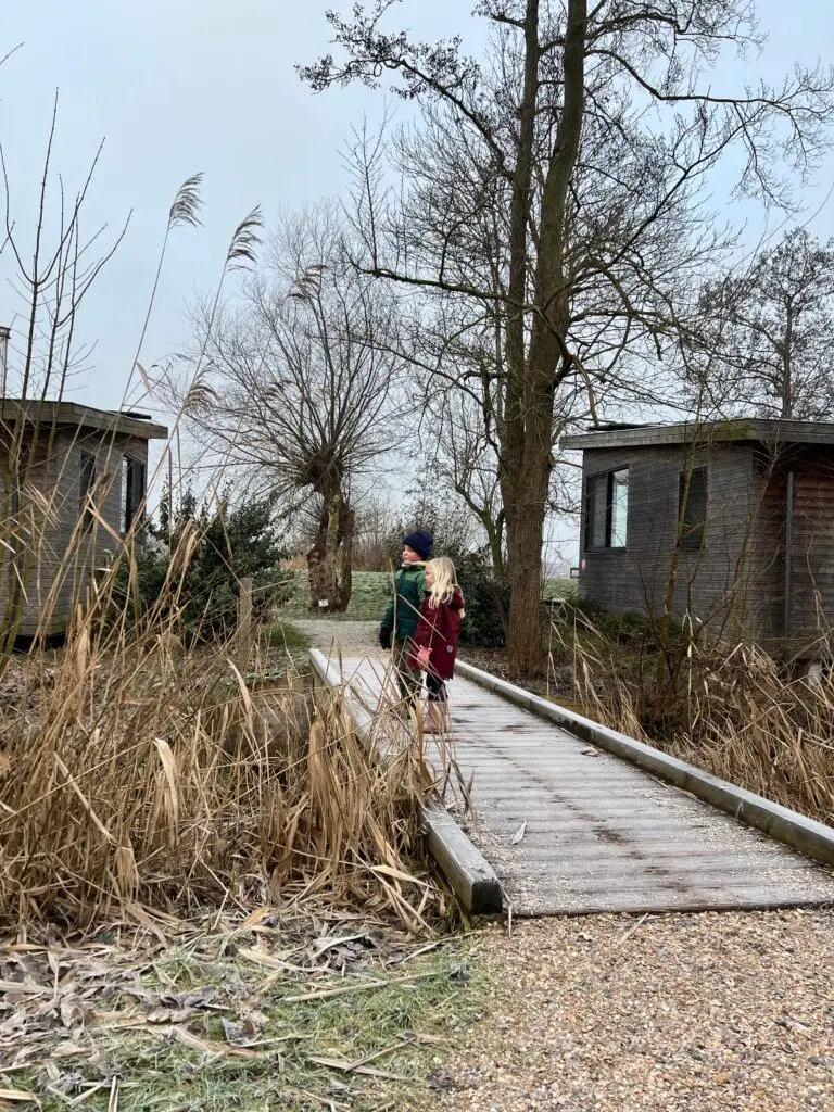 Kinderen lopen over houten bruggetje tussen de lodges van Pean Buiten