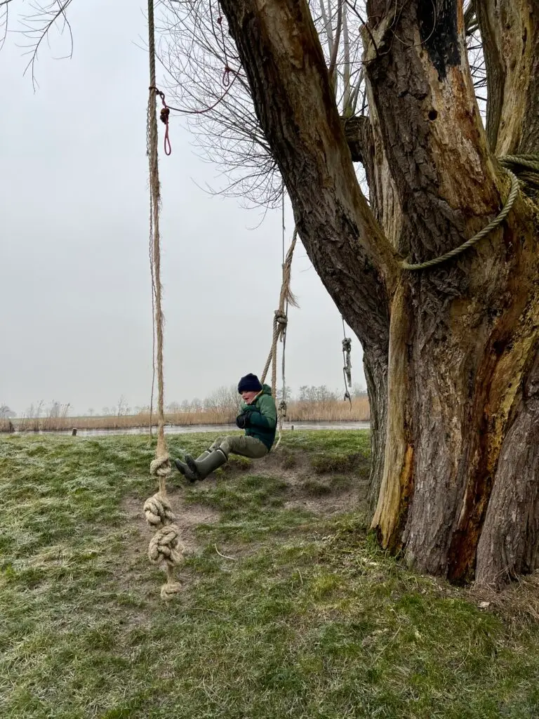 Kind slingert aan touw in boom bij Pean Buiten, overnachten aan het water Friesland