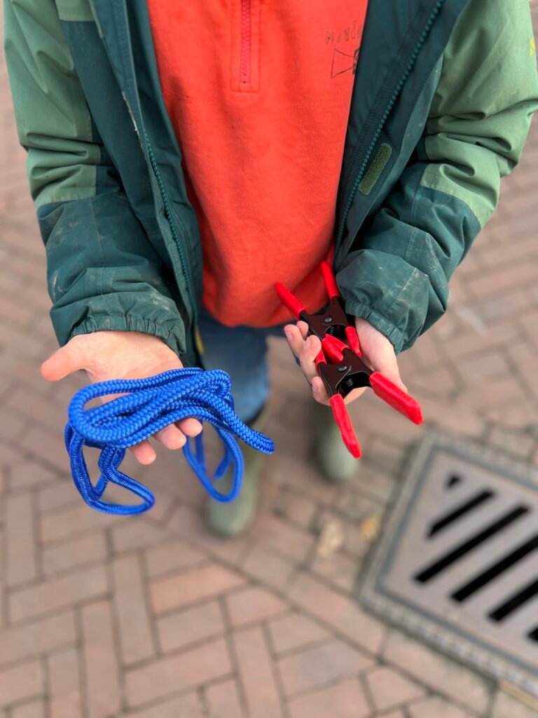 Kinderen bouwen een hut met grote knijpers en touw in de bosjes