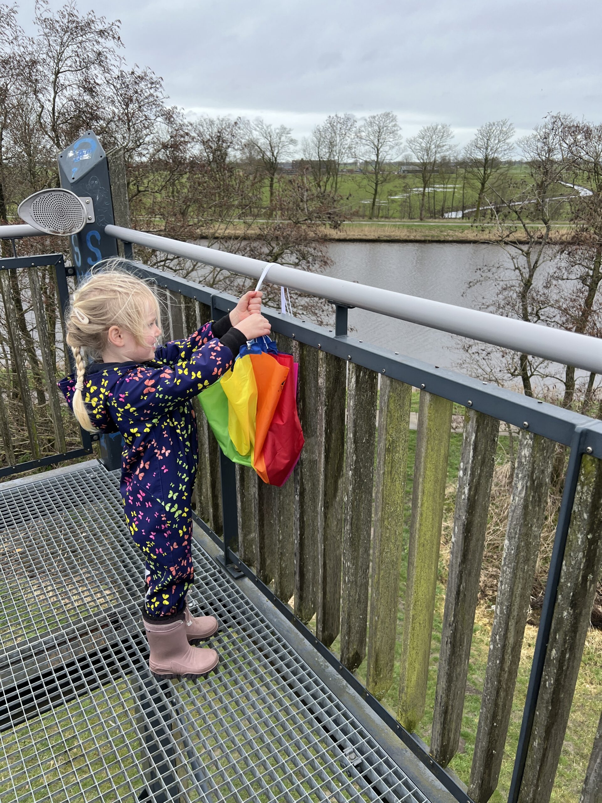 Kind gooit een speelgoed parachute van een uitkijktoren tijdens buitenspelen