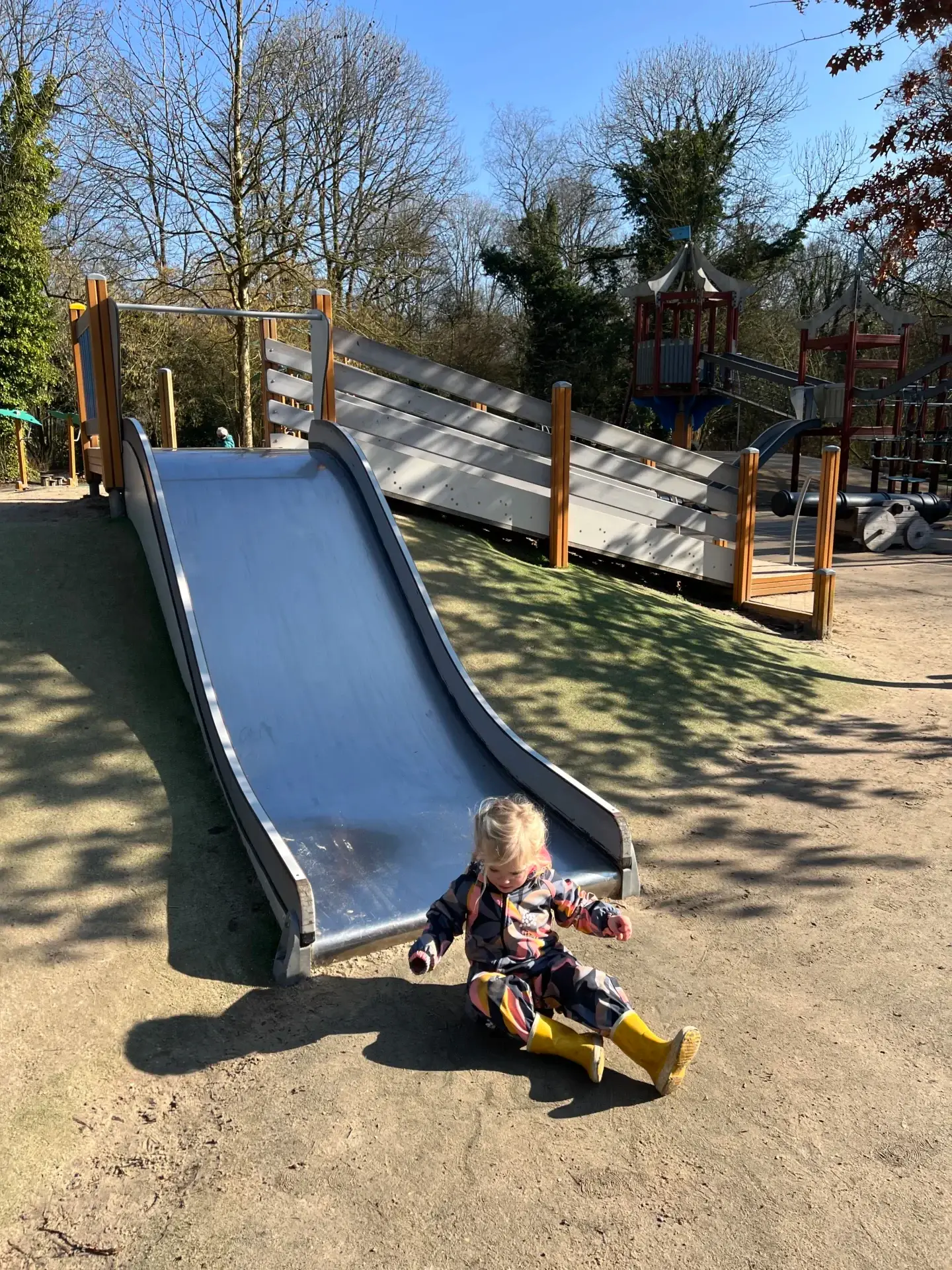 Kind dat van de glijbaan gaat in de speeltuin van het Stadspark