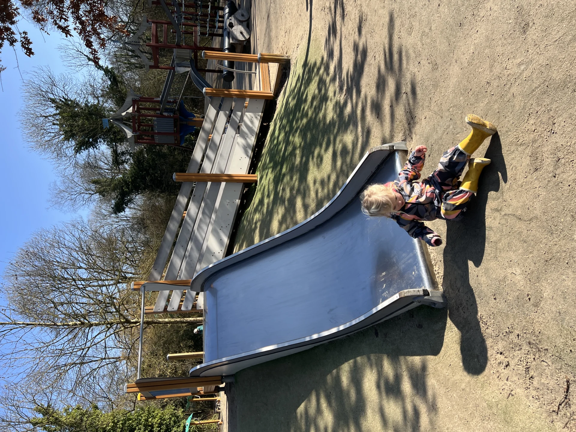 Kind dat van de glijbaan gaat in de speeltuin van het Stadspark