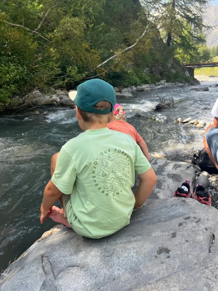 Kind bij beekje in de bergen van Zwitserland met Vaude shirt