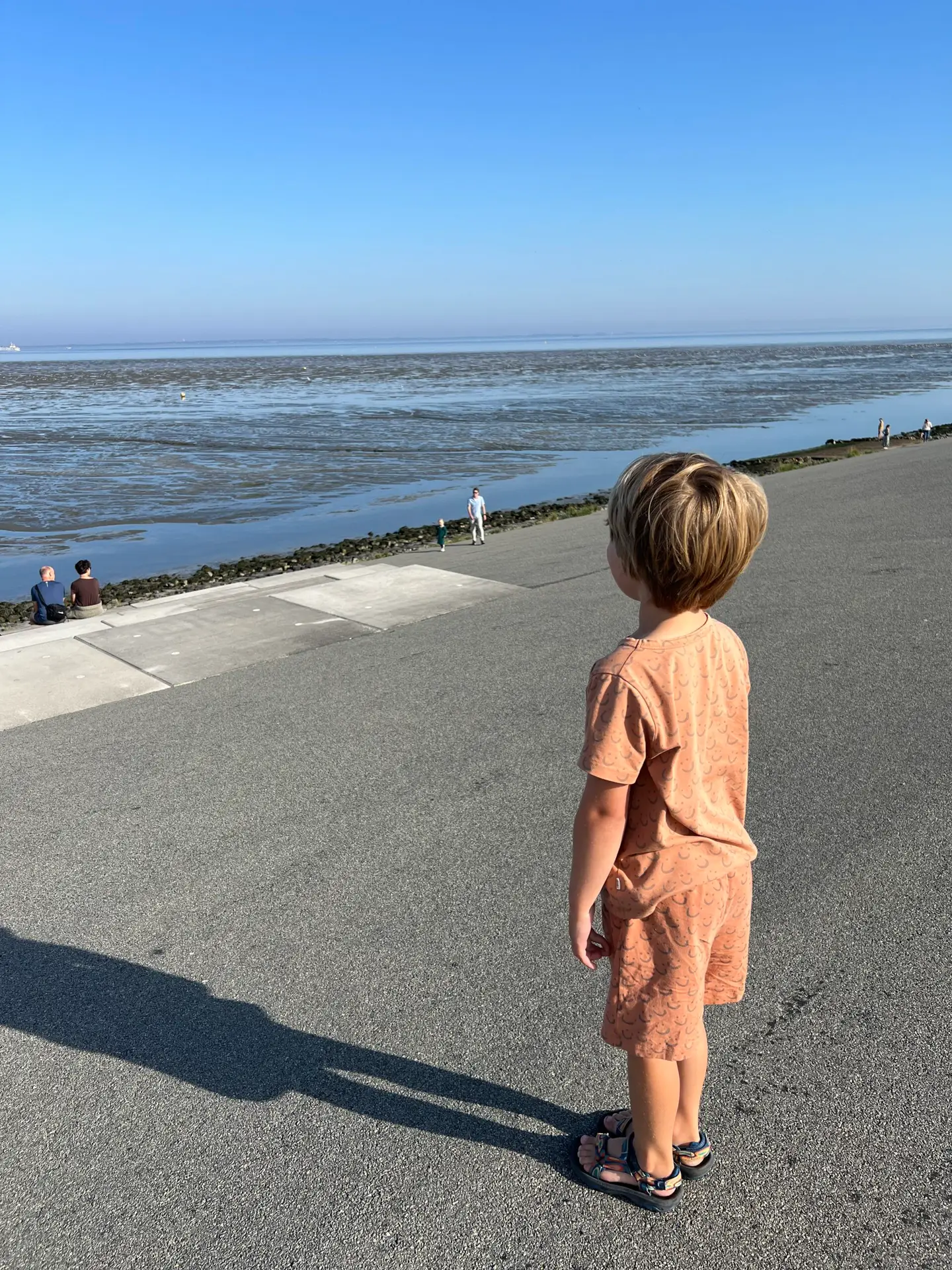 Kind zit op de Waddentribune met uitzicht op de Waddenzee