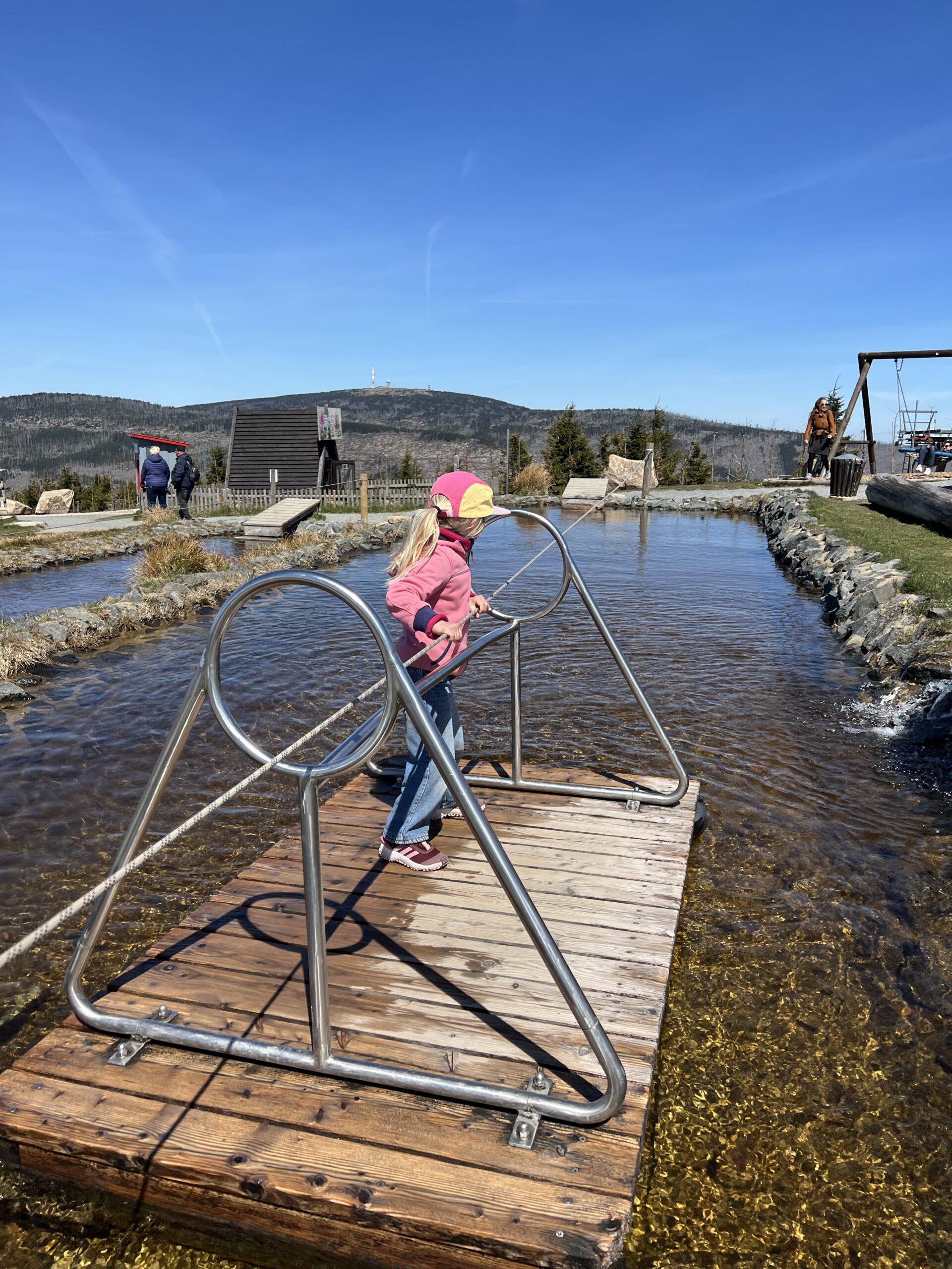 Kind vaart op een vlot over het water in de speeltuin op de Wurmberg in de Harz tijdens de meivakantie